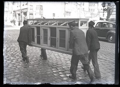 Bărbați transportând un corp de mobilier pe strada Academiei